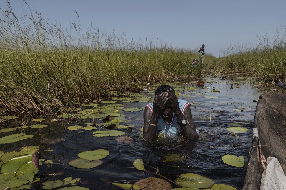 Duk, an ethnic Nuer South Sudanese, bathes in the swamp of the White Nile river near Mayendit, Unity State, South Sudan, November 23, 2022. Duk is originally from Mayendit, a village that has almost entirely disappeared by flood waters. In 2020 it was possible to reach Mayendit by land; today the only way to reach the village is an eight hours canoe trip.