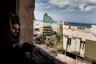 A fighter loyal to Libya's Government of National Accord is seen while looking into a mirror as he attempts to spot Islamic State positions in District 3, the last IS stronghold in Sirte, on September 23, 2016.