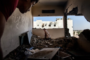 Fighters, supporters of Libya's Tripoli-based Government of National Accord, move in a destroyed building close to the frontline as they attempt to spot Islamic State positions in District 3, the last IS stronghold in Sirte, on September 23, 2016.