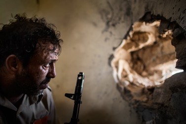 A fighter loyal to Libya's Government of National Accord is seen while looking into a wall' hole as he attempts to spot Islamic State positions in District 3, the last IS stronghold in Sirte, on September 22, 2016.