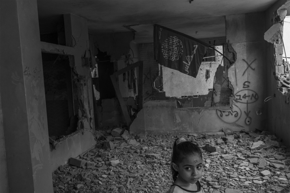 A Palestinian child in a destroyed building during the Israeli army's nighttime raid in the Askar refugee camp in Nablus on October 29, 2023. In the background, a Hamas flag hangs on the remnants of the building.